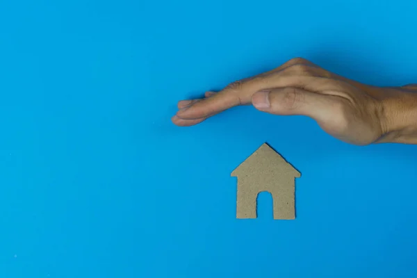 Koncepcja ubezpieczenia nieruchomości. Ręka człowieka chronić mały dom m — Zdjęcie stockowe
