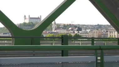 Bratislava 'da Bratislava kalesinin arka planında bir köprüden geçen bisikletçiler.