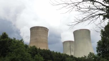Yeşil ağaçların arkasında tüten nükleer enerji santrali