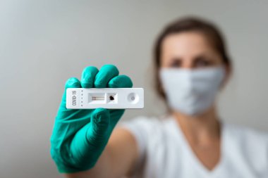 Kadın doktor yeşil lateks eldiven giymiş Covid-19 hızlı test gösteriyor.