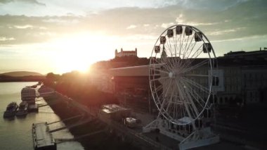 Bratislava dönme dolap, kale ve Tuna Nehri drone fotoğrafı gün batımında.