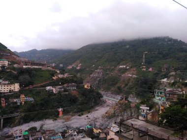 İki tarafında güzel dağları olan bir nehir kenarı.