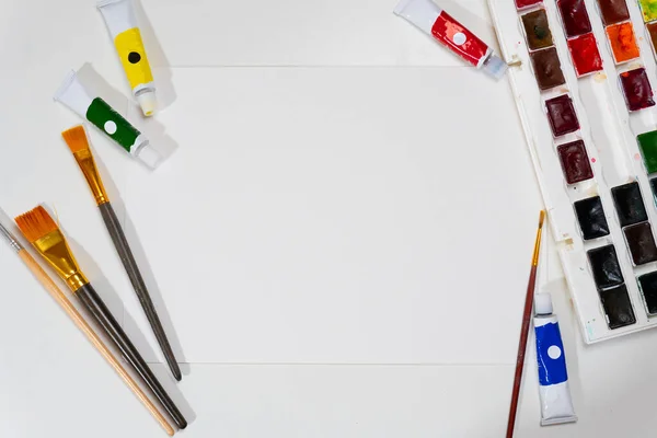Hoja de papel blanco y pinceles y pinturas sobre la mesa — Foto de Stock