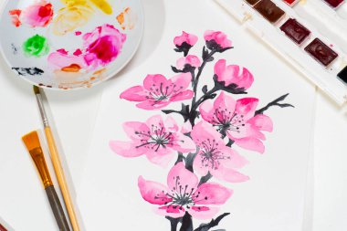 Ressam masasında pembe çiçekler olan suluboya bir resim. Üst görünüm.