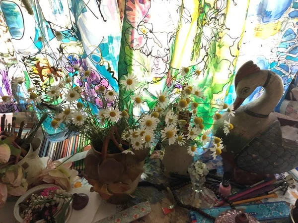 İçinde papatyalar, vazolar ve masa kağıdında papatyalar ve papatyalar olan yaz masası. Kalemler, sanatsal perdeler, güzel bir buket.