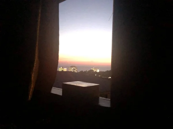 Karanlık zaman, gün batımı, deniz manzarası ve kasaba silueti. 