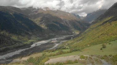 Dağ manzaralı nehir, karlı dağ tepeleri, yeşil çayırlar, Svaneti, Georgia 'daki tarlalar.