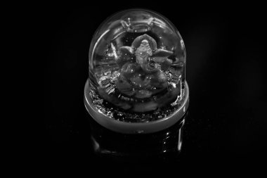 Hindu tanrısı Ganesha heykeli siyah parlak arkaplanda yansımalı..