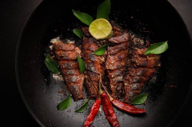 Koyu arkaplanda lezzetli alabalık balığı olan kızartma tavası.