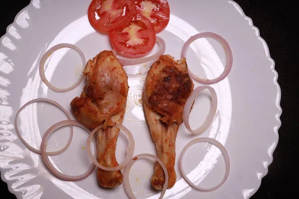 Lezzetli kızarmış tavuk budu, beyaz tabakta sebze salatasıyla servis ediliyor.
