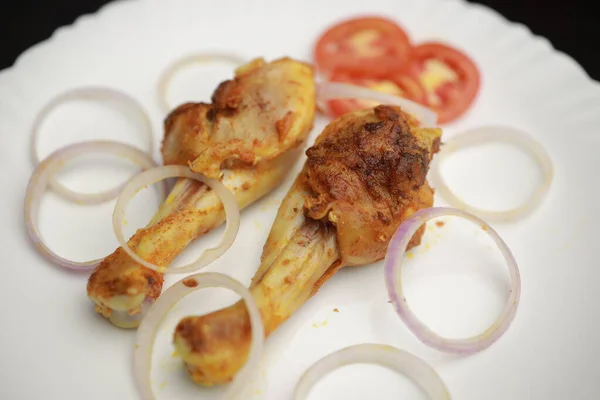 Lezzetli kızarmış tavuk budu, beyaz tabakta sebze salatasıyla servis ediliyor.