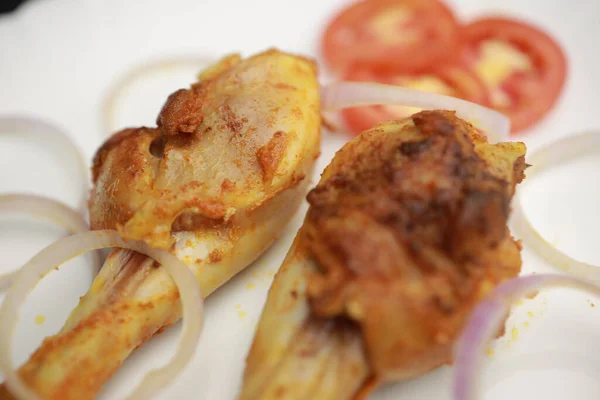 Lezzetli kızarmış tavuk budu, beyaz tabakta sebze salatasıyla servis ediliyor.