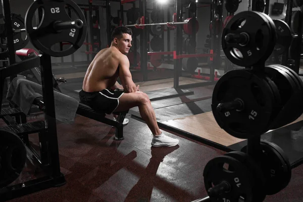 Athlete professional athlete rests before exercise on bench in gym