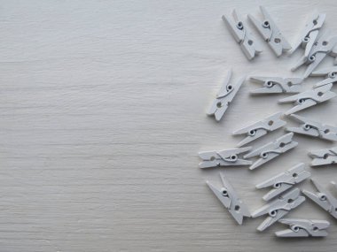 Beyaz ahşap arka plandaki fotoğraflar için küçük tahta mandallar, yakın plan.