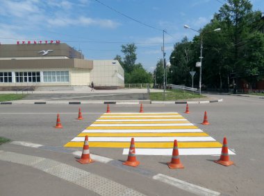 Yol üzerindeki turuncu trafik ışığı konileri boyanmış bir yaya geçidi..                