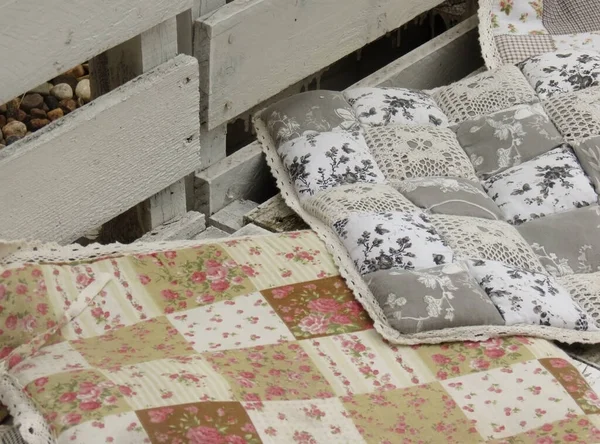 Soft pillows with floral print on a white wooden bench in the loft style on the street, close-up