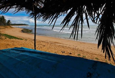 Güzel renkli Praia do Forte Beach, Bahia, saman kulübesi ve kumsalda yatan balıkçı teknesinin manzarası. Çerçeveli yalnızlık sahnesi. Kuzeydoğudaki turistler için ünlü yaz gezisi beldesi.