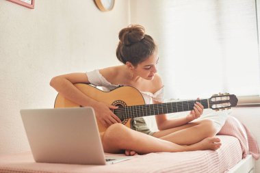 Gitarı dizüstü bilgisayarla birlikte öğrenen kız