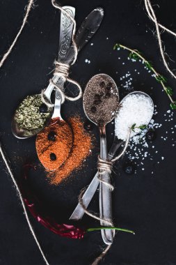 Taş üzerinde farklı kaşık içinde baharatlar plaka arka plan kayrak. Rustik vintage renk tonlama..