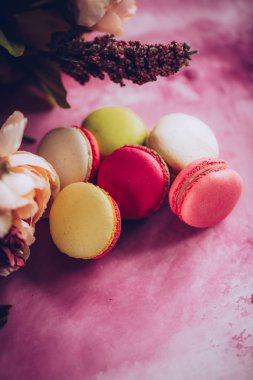 Pembe bir arka plan üzerinde kek kurabiye. Üstten görünüm macaron tatlı kapatın. Pastel pembe, sarı renkler renkli badem çerezler. Vintage tarzı tonlama.