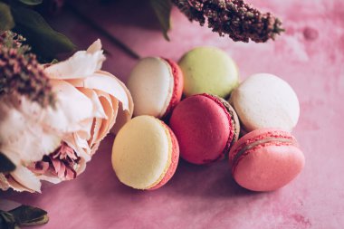 Pembe bir arka plan üzerinde kek kurabiye. Üstten görünüm macaron tatlı kapatın. Pastel pembe, sarı renkler renkli badem çerezler. Vintage tarzı tonlama.