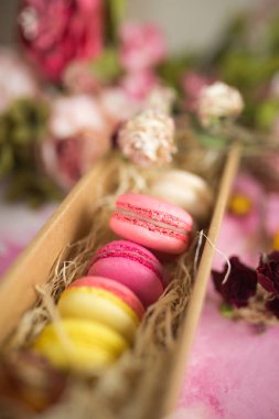 Pasta Kurabiye hediye kutusunda parlak arka planda satır. Üstten görünüm macaron tatlı kapatın. Pastel pembe, sarı renkler renkli badem çerezler. Vintage tarzı.