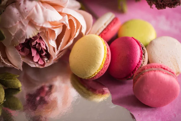 Pembe bir arka plan üzerinde kek kurabiye. Üstten görünüm macaron tatlı kapatın. Pastel pembe, sarı renkler renkli badem çerezler. Vintage tarzı tonlama.