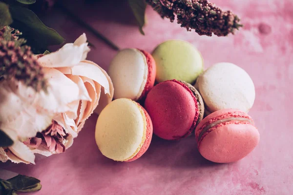 Pembe bir arka plan üzerinde kek kurabiye. Üstten görünüm macaron tatlı kapatın. Pastel pembe, sarı renkler renkli badem çerezler. Vintage tarzı tonlama.