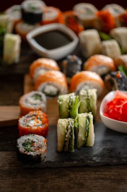 Suşi yemek fotoğraf ayarlayın. Rulo kahverengi ahşap ve kayrak tabakta. Suşi yakın çekim.