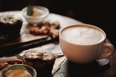 Fincan kahve ve tatlı ahşap masa backgrouund kafede üzerinde gıda görüntüsünü kapatın. Eğilim sıcak tonlama. Küçük bir alan derinliği ile fotoğraf.