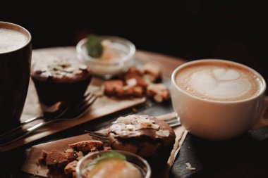 Fincan kahve ve tatlı ahşap masa arka planda Cafe gıda görüntüsünü kapatın. Eğilim sıcak tonlama. Küçük bir alan derinliği ile fotoğraf