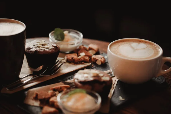 Cerrar imagen de la comida de la taza de café y postre en el fondo de la mesa de madera en la cafetería. Tendencia tonificación cálida. Foto con una pequeña profundidad de campo — Foto de Stock