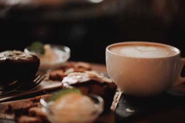 Fincan kahve ve tatlı ahşap masa arka planda Cafe gıda görüntüsünü kapatın. Eğilim sıcak tonlama. Küçük bir alan derinliği ile fotoğraf