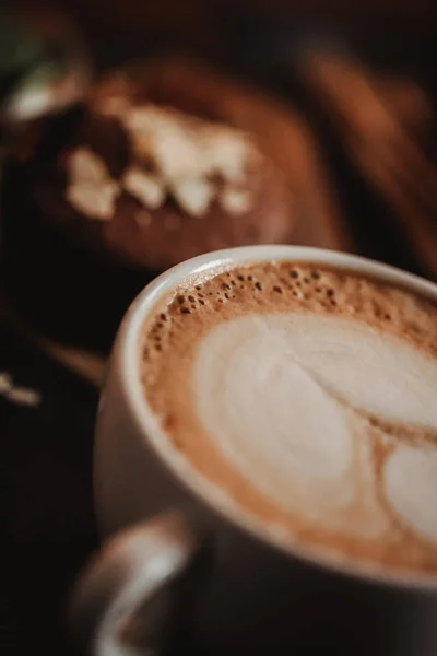 Cerrar imagen de la comida de la taza de café con la imagen en una espuma sobre el fondo de la mesa de madera en la cafetería. Tendencia tonificación cálida. Foto con una pequeña profundidad de campo — Foto de Stock