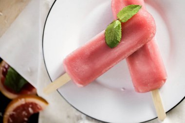 Yaban mersini dondurma ya da dondurmayı yeşil nane ile beyaz sanat plaka üzerinde bırakır. Rustik renk stili. Vintage tarzı dondurulmuş meyve suyu. Üstten görünüm fotoğraf.