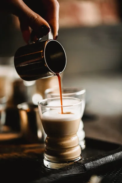 Рука бариста, що робить каву в кафе. Кубок традиційного еспресо з молоком. Кава вливається в склянки. Тоноване зображення — стокове фото