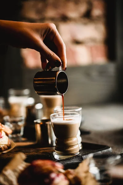 Mano de barista haciendo café en el café. Taza de espresso tradicional con leche. Café vertiendo en vasos de chupito. Imagen tonificada — Foto de Stock