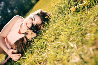 Kedi ile çim üzerinde yalan kız. Bahar ya da yaz sıcak hava kavramı. Bokeh arka plan. İki yüz renk maskesi ile zencefil yavru kedi