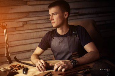 Deri kemer deri atölyesinde çalışma süreci. Adam holding işçiliği aracı ve çalışma. Tanner eski Tabakhane içinde. Ahşap masa arka plan. Metin ve tasarım için ılık ışık.