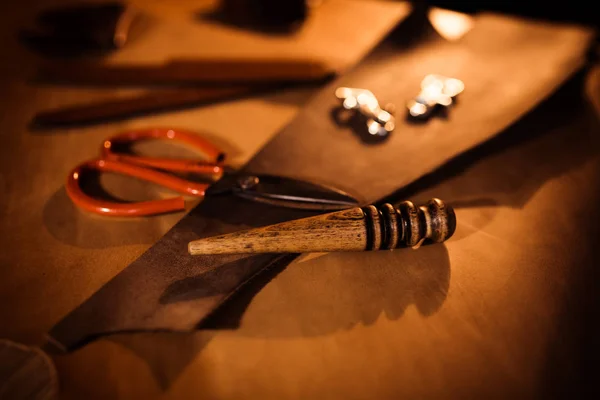 Arbeitsprozess des Ledergürtels in der Lederwerkstatt. Gerber in der alten Gerberei. Bastelwerkzeug auf Holztischhintergrund. — Stockfoto