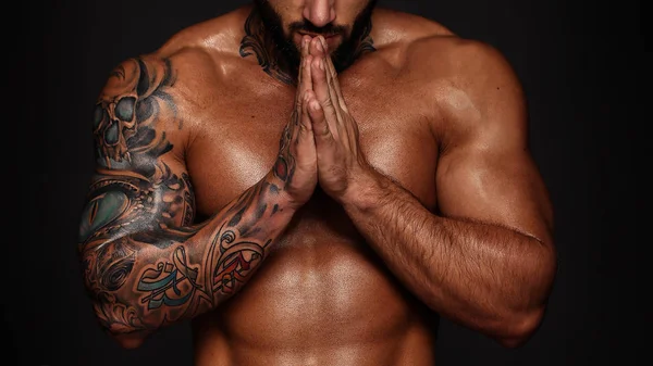 Bodybuilder with muscle torso. Banner image of sexy man with muscular body. Portrait of sexi male model. Hot macho in prayerful pose with folded hands on black background. 16 in 9 crop for design — Stock Photo, Image