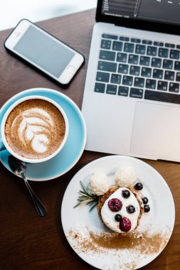 Üstten Görünüm tasarımcıları yer. Serbest çalışma alanı. Defter ile cep telefonu, fincan kahve ve tatlı ahşap tablo