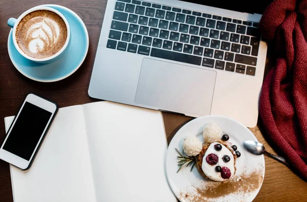 Draufsicht auf das Bürodesign-Konzept. Freiberufler. Kopiernotiz, Notizbuch, Tasse Kaffee und Dessert auf Holztisch — Stockfoto