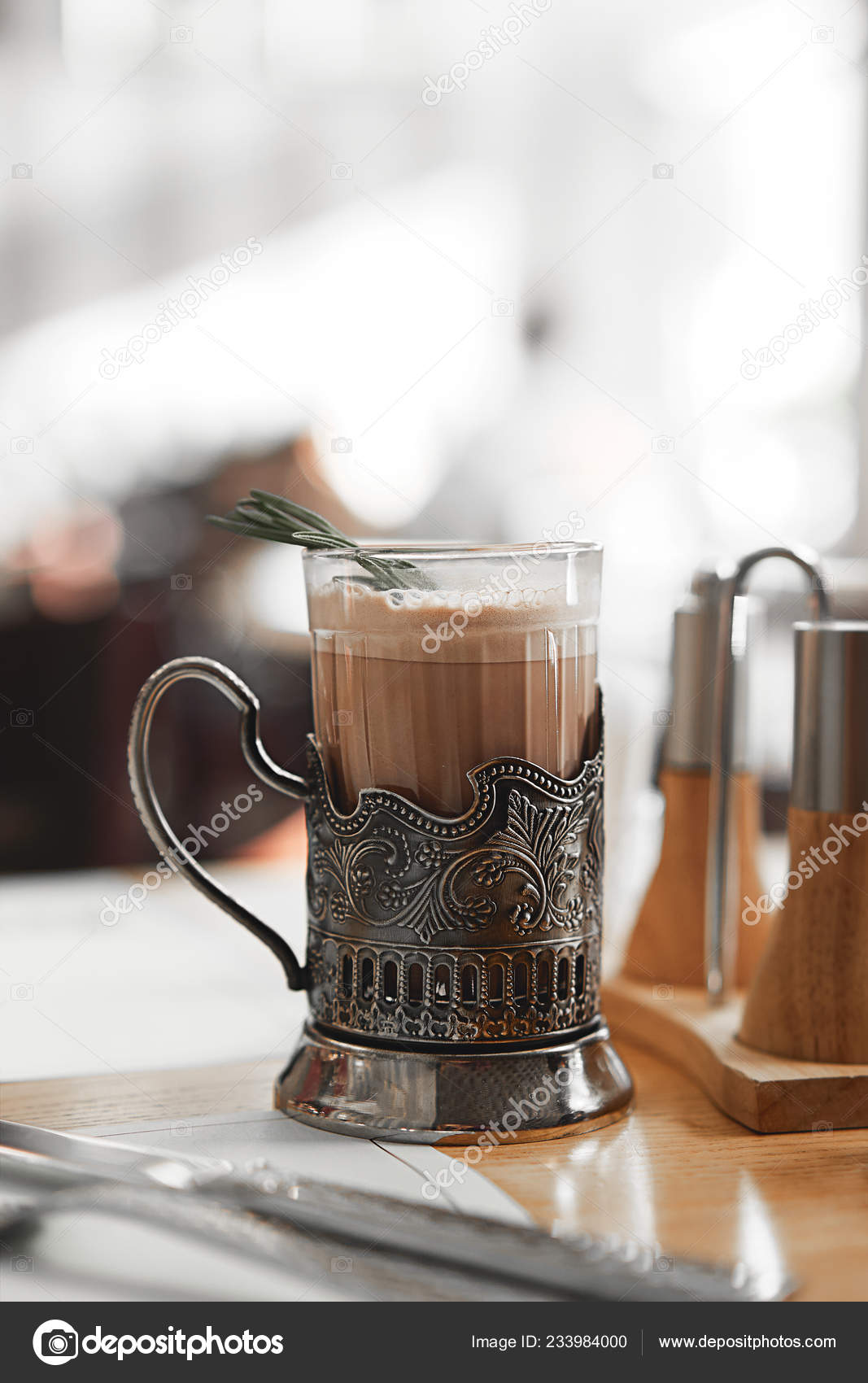 A mug of hot cocoa with a rosemary branch in a vintage metal cup holder.  Retro style food photo concept. Blurred background and copy space for text,  design, lettering Stock Photo by ©
