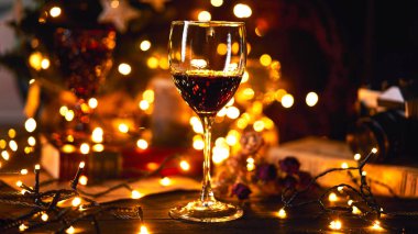 Afiş boyutu 16 9. Festival atmosferi akşam bir kadeh kırmızı şarap ile. Işık bokeh arka plan üzerinde. Noel, yeni yıl veya Saint Valentine tatil. Altın rengi ve yumuşak odak