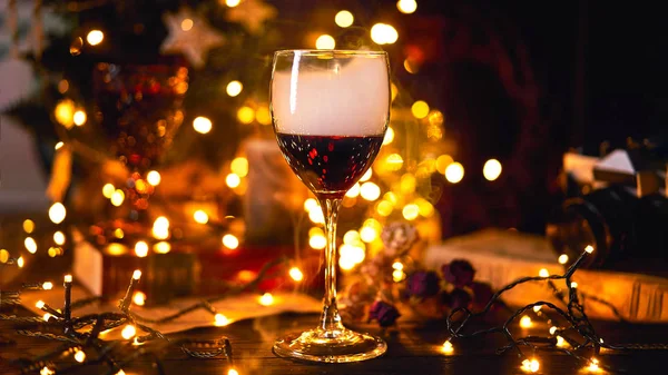 Banner tamaño 16 en 9. Ambiente festivo con una copa de vino tinto. Humo arrastrándose en vidrio y fondo bokeh luz. Navidad, Año Nuevo o San Valentín Holiday.Golden color y enfoque suave — Foto de Stock