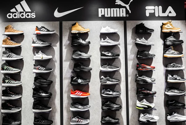 Nurmberg, GERMANY - 27 Februari 2019: The NIKE, ADIDAS, PUMA dan FILA black man sneakers on the shell in the shop. Fashionable kaki memakai sepatu — Stok Foto