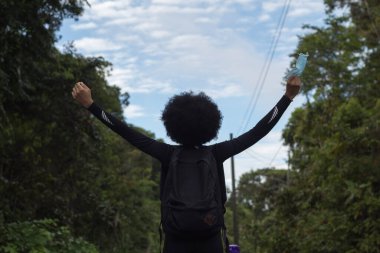 Kot giymiş, kolları havada siyah bir kadın.