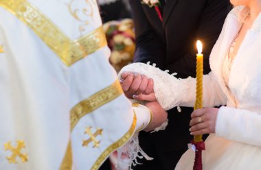 Rahip gelinin ve damadın elini tutuyor.