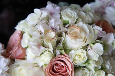 Gelinin parlak bir buketinde alyanslar, yakın plan..